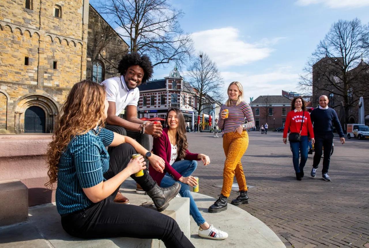 Groep jongeren zit te praten op een plein in het centrum